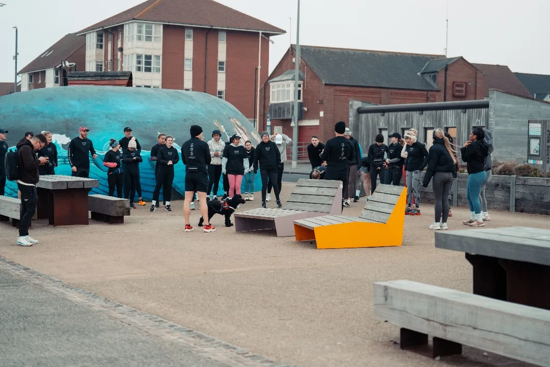 303 Run Club gathered by the whale sculpture on the seafront plaza at Seaburn