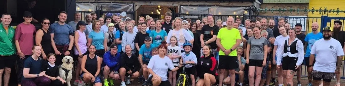 Lace Up with Lucy gathered outside the venue after a run, a golden retriever at the front