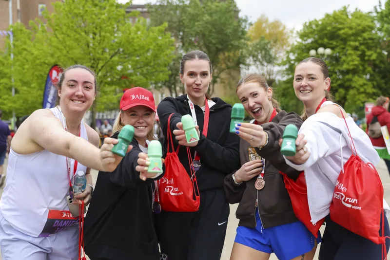 Five runners holding Mitchum products and AJ Bell Great Run Series bags after an event