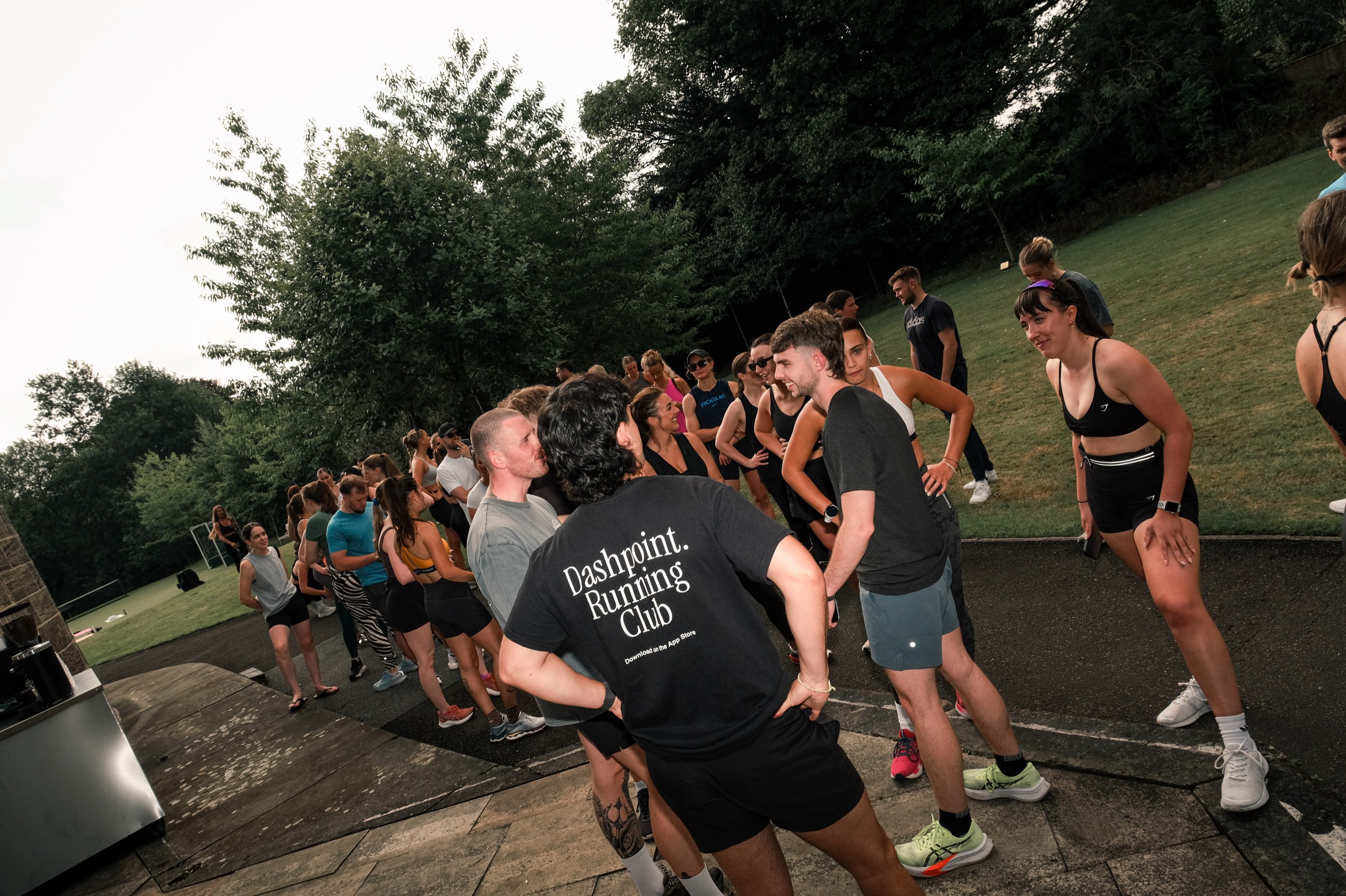 A DashPoint Running Club group warming up together on a park path before an evening session